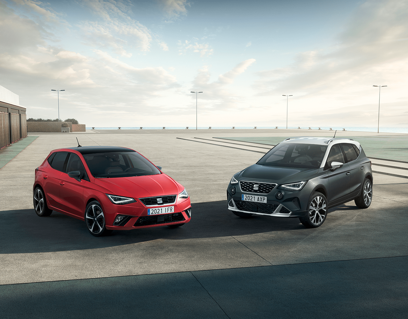 Image of a red sedan and grey SUV angled towards each other in a parking lot showcasing a sample of SEAT S.A. vehicles.